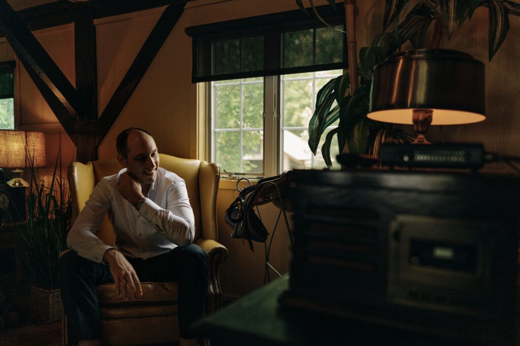 Cinematic photograph of groom before the ceremony at rustic wedding.