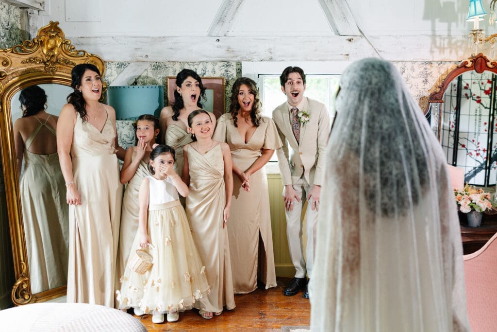 Bridesmaids reacting surprised and happy at seeing bride in dress. 
