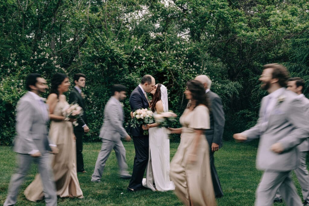 Motion blur wedding party picture while bride and groom kisss.