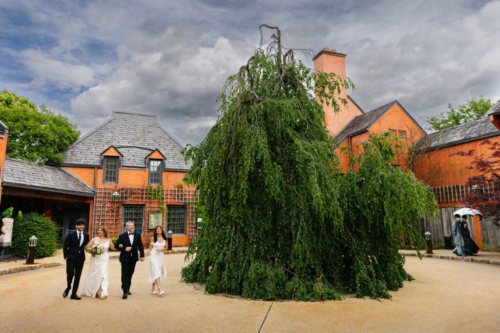 Bride and groom walking with their adult children outside Rat's Restaurant during a 25th wedding anniversary vow renewal in Hamilton Township, New Jersey.