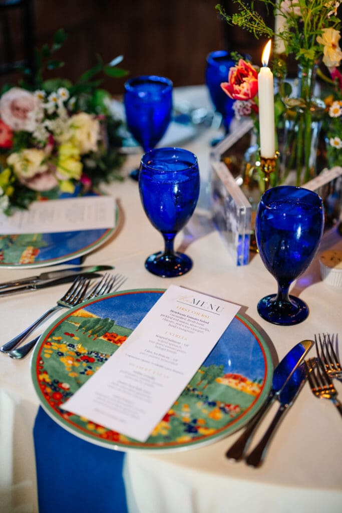 Monet-inspired place setting with blue glassware at a wedding  celebration at Rat's Restaurant.