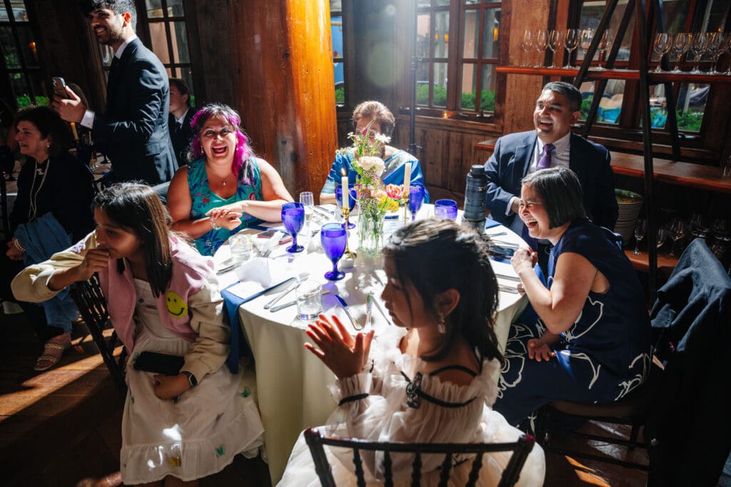Family members laughing during speeches at a 25th wedding anniversary celebration at Rat's Restaurant.