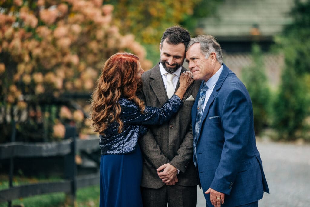 Emotional portrait of mother and father hugging the groom.