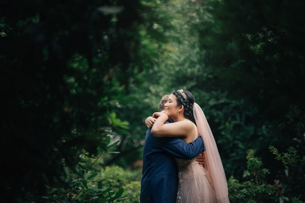 Smiling bride hugging her husband at their wedding in Sayen House and Gardens, NJ